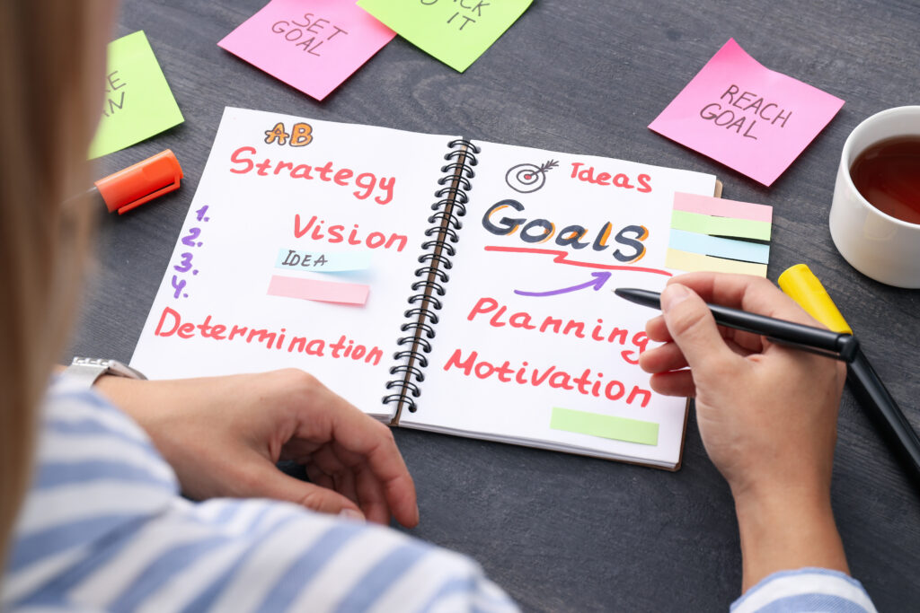 A person is sitting at a desk and making notes in a notebook related to her career planning.